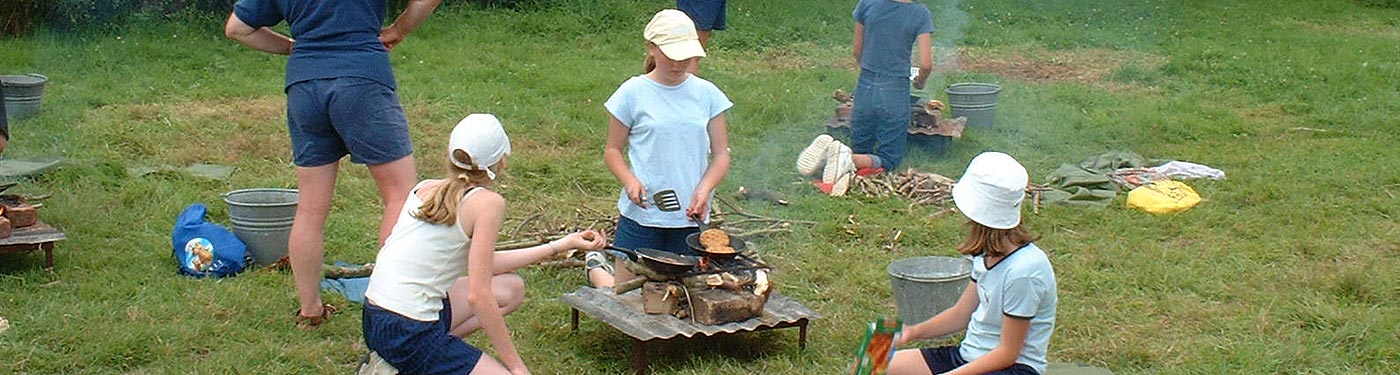 girl guides cooking lunch at campsite